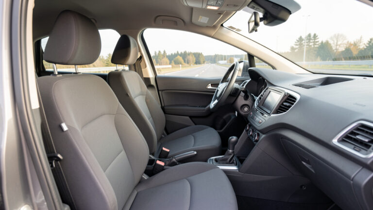 Intérieur moderne d’une voiture montrant le siège conducteur, le volant, l’appuie-tête, les pédales, la ceinture et les rétroviseurs correctement ajustés.